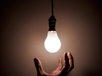 Sharing ideas hand under a lit lightbulb