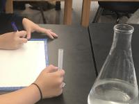 students measuring the volume of the liquid in a 10mL graduated cylinder