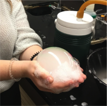 student holding bubble produced from hose of homemade cooler device