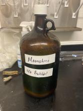 brown jug with handwritten text: Moonshine, aka bubbles!