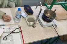student watching pot of water on hotplate with water