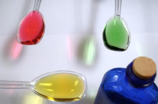 blue Milk of Magnesia bottle and three spoons each with a different color of liquid