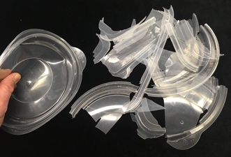 Polypropylene container lids (at left) flexing at room temperature and (at right) after breaking apart in a brittle manner at -23C