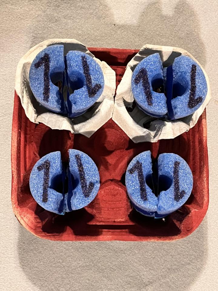 Cup holder arrangements featuring electrons represented by a variety of items