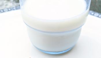 clear glass cup half full of milk & two chili peppers next to it