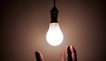 hand under a lit lightbulb 