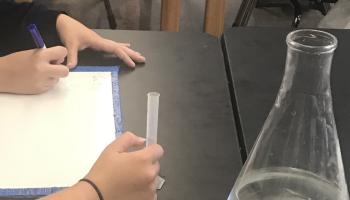 students measuring the volume of the liquid in a 10mL graduated cylinder