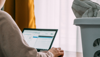 adult using laptop with laundry basket nearby