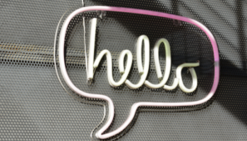 neon sign w/ "hello" in cursive and surrounded by speech bubble shape