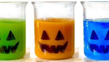 colored solutions in beakers decorated with a Jack-o-lantern face