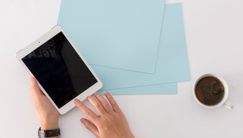 hands holding iPad at a table with coffee