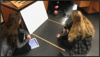 students shooting pennies under whiteboard