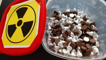 wrapped and unwrapped chocolate kiss candies in a container with radioactive symbol on lid