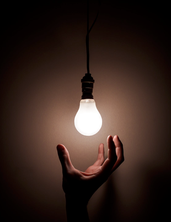 hand under lit lightbulb