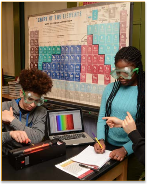 two students wearing goggles and working on a lab